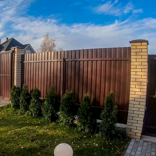 Fence and gate made of brown corrugated metal profile